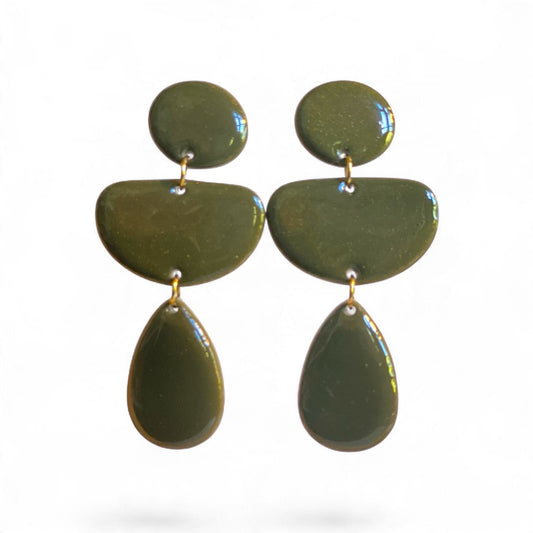 Boucles d’oreilles pendantes LOUMA vert kaki en pâte polymère façonnée à la main, composées de trois formes géométriques arrondies reliées par des anneaux en acier inoxydable.