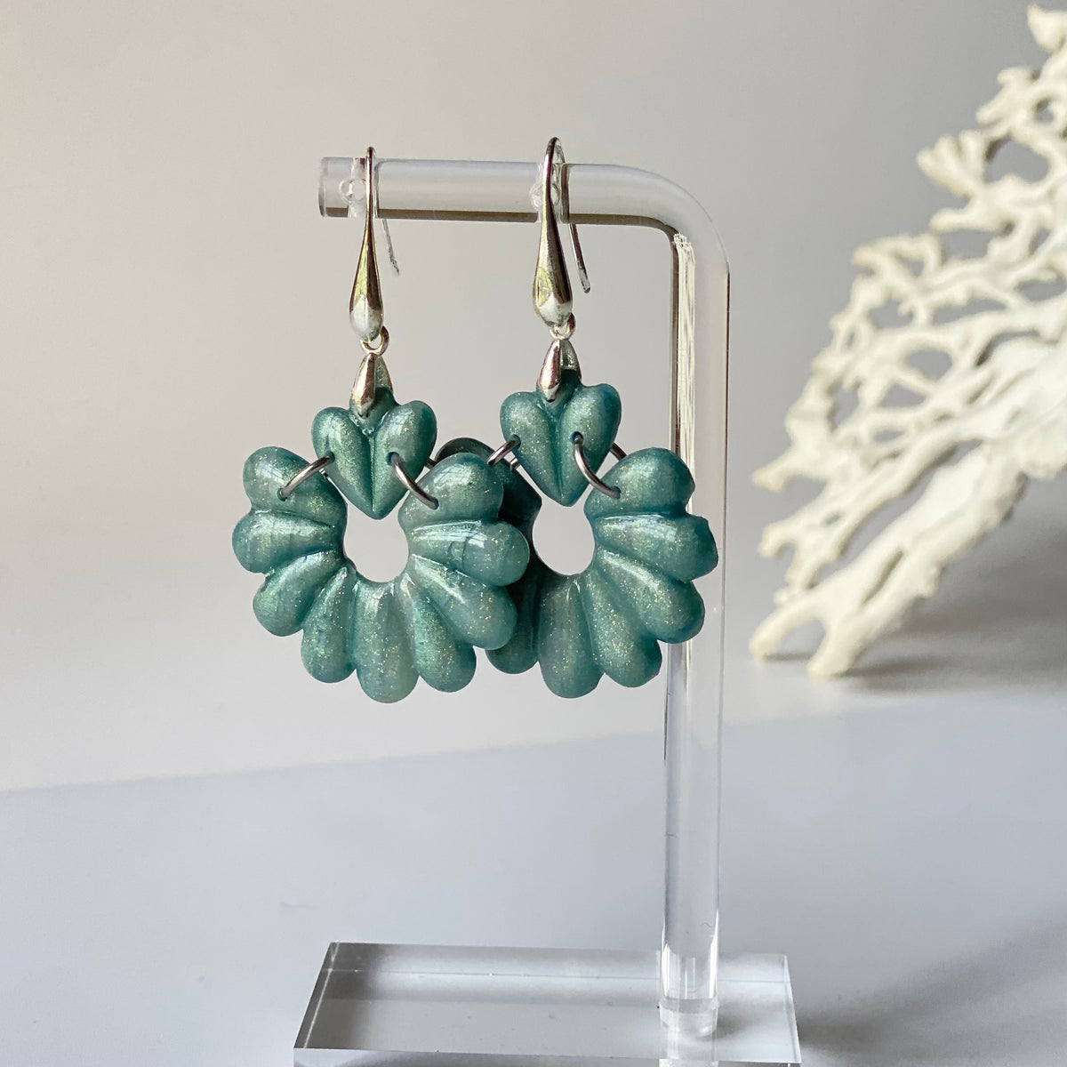 Variante turquoise foncé métallisé des boucles d’oreilles GAIA, création artisanale en pâte polymère avec cœur stylisé, fleur ajourée et attaches dorées.